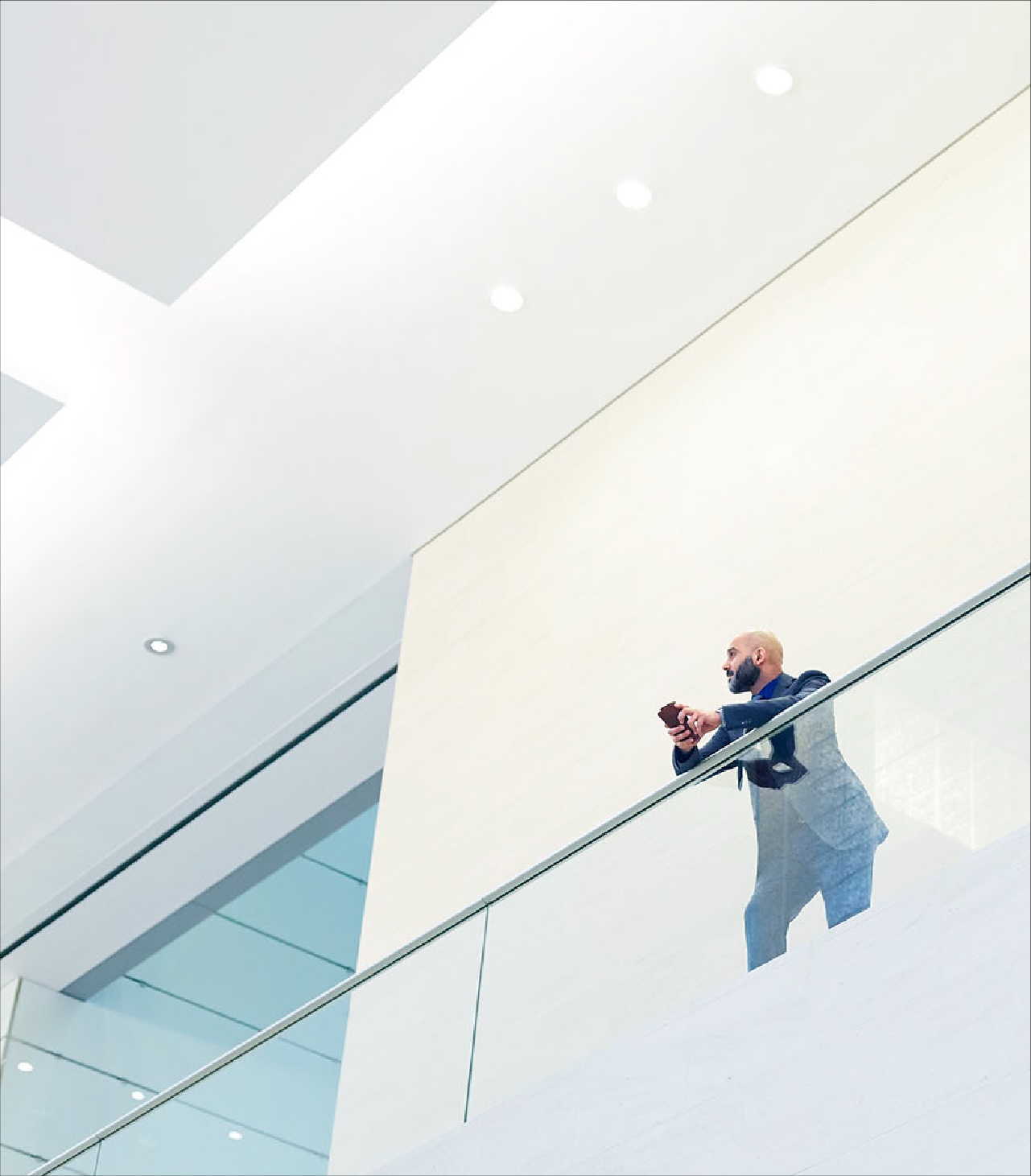 Person standing on a modern office balcony using a mobile device, representing digital governance and AI compliance planning.
