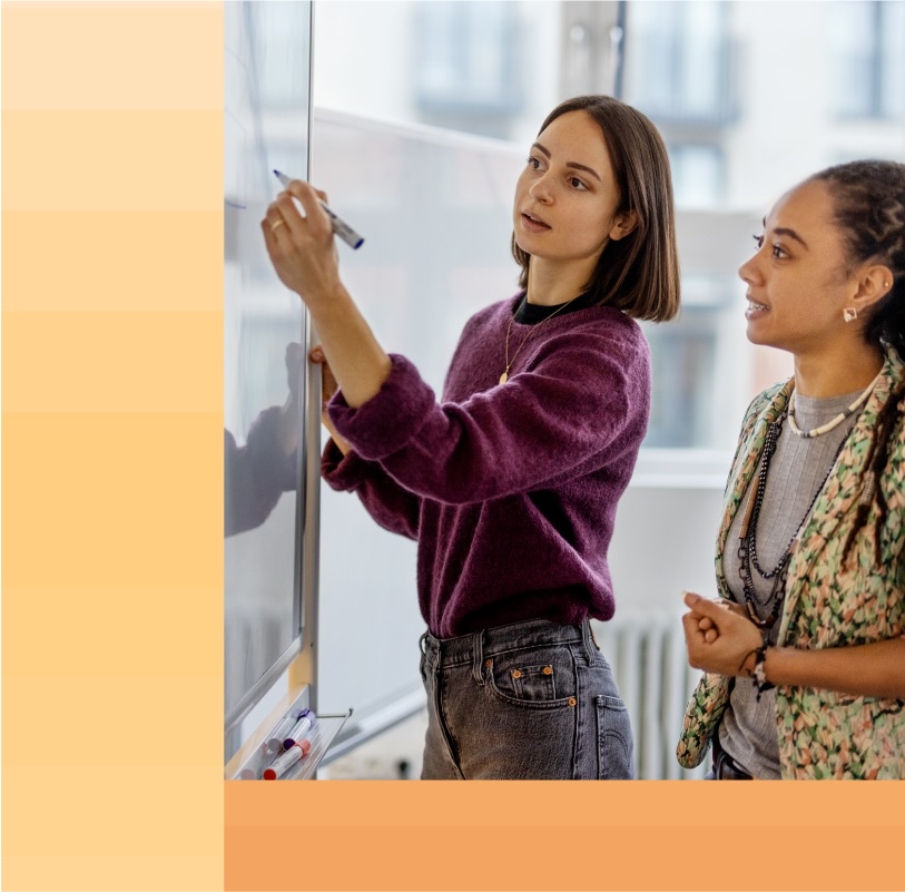 Woman writes on a whiteboard during a planning session with her coworker.